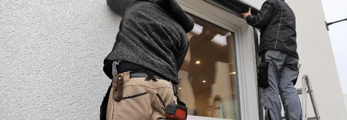 Zwei Personen montieren einen Rollladenkasten an einem Haus.